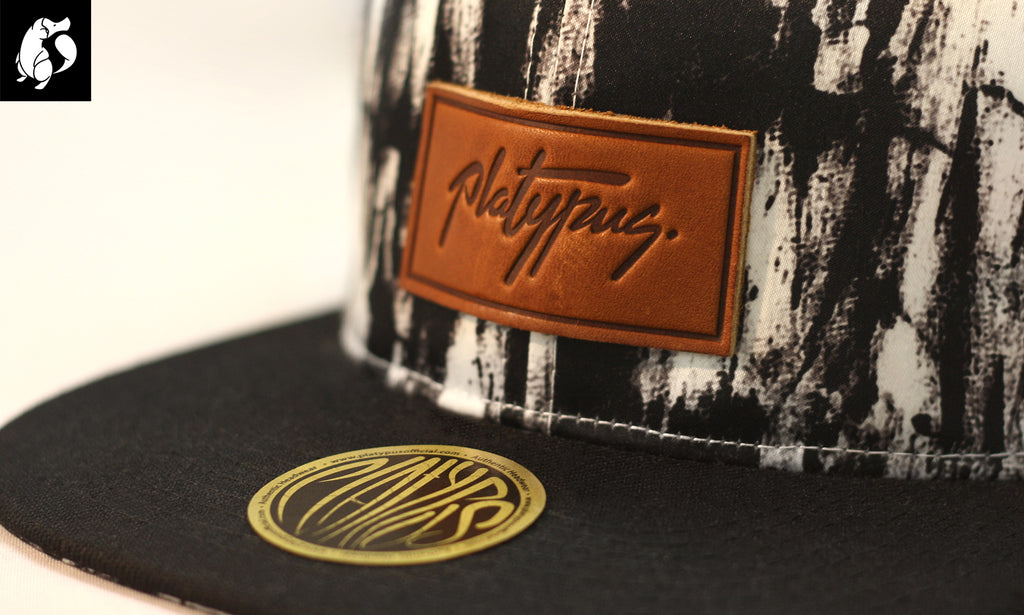 Close up of charcoal arty crown snapback cap and leather Platypus patch