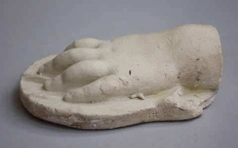 photo of plaster cast of baby hand on low panel with gray background