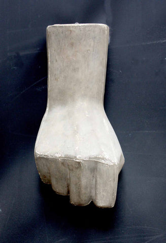 photo of plaster cast of hand in a fist hanging on a dark-colored wall