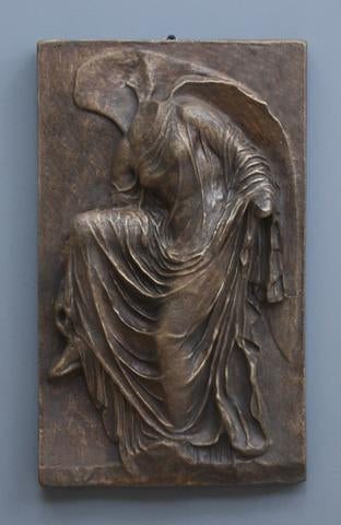 photo of cast of sculpture relief of robed figure, head now missing, reaching for her sandal in Bronze Patina on a gray background