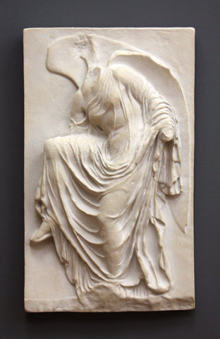 photo of cast of sculpture relief of robed figure, head now missing, reaching for her sandal in Sandstone Patina on a dark gray background