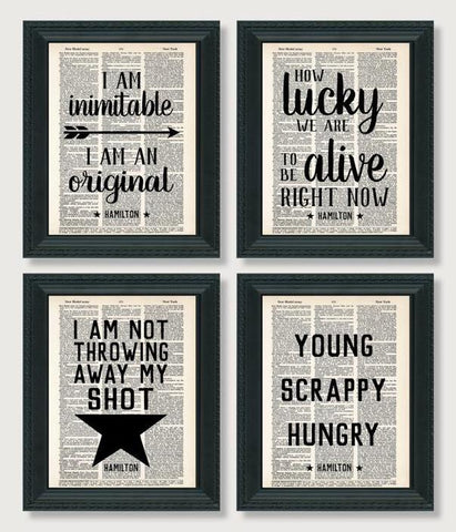 photo of four black frames with prints inside featuring large black text and symbols on dictionary pages