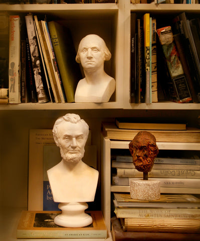 sculpture busts on a table and bookshelf