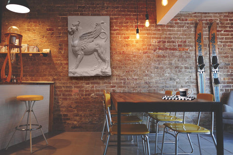 Photo of Plaster Cast of Griffin on a brick wall in a chic restaurant with a bar, table, and skis leaning against the wall