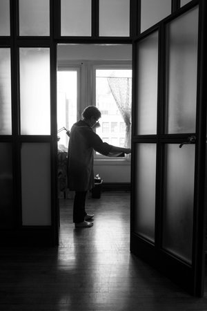 Andrea Aranow stands in a doorway in her studio, framed and backlit by windows