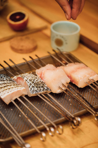 Daniel Benhaim seasons skewered filets of Japanese sea bass.