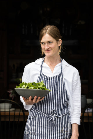 Annemarie Ahearn poses holding a handmade ceramic bowl filled with fresh parsley leaves