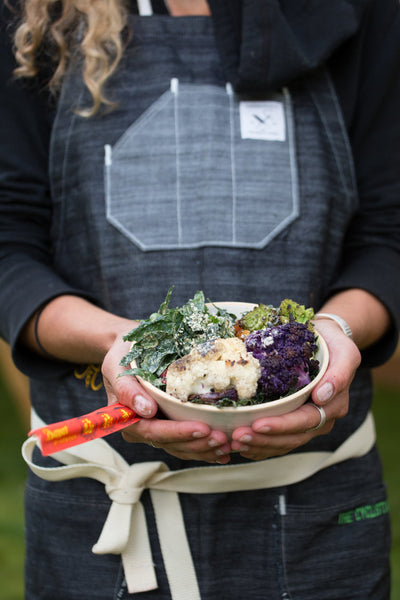 Heidi Rentz of The Cyclist's Menu holds a handmade ceramic bowl filled with colorful roasted vegetables. 