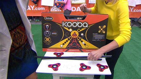 KOOBA game in it's packaging stands on a table surrounded by aeros and sticks to play the game with in the TODAY plaza.