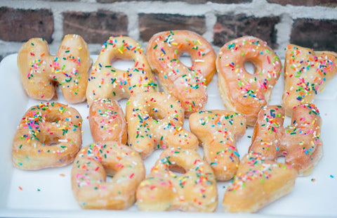 Glazed donuts spelling out Happy Birthday covered in sprinkles.