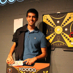 Joint third place KOOBA tournament finalist in front of the tournament board with his t-shirt and KOOBA Game prize.