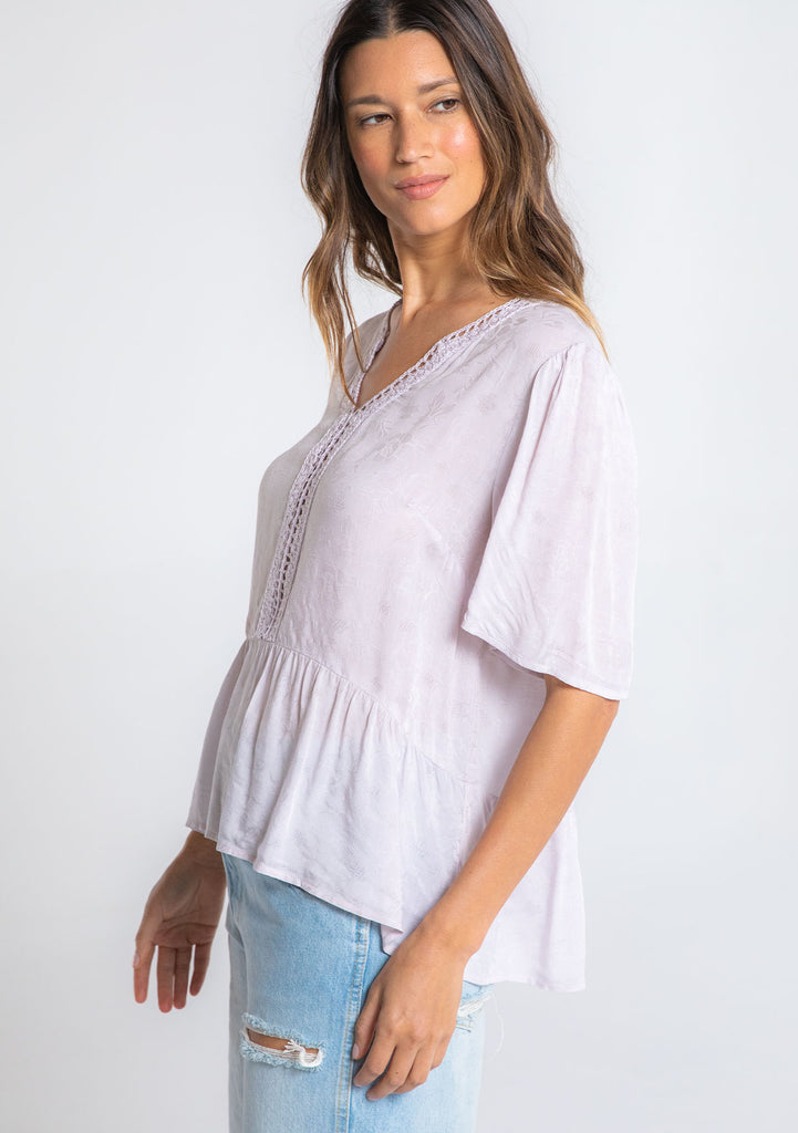 [Color: Orchid Tint] A model wearing a flowy light purple short sleeve top.