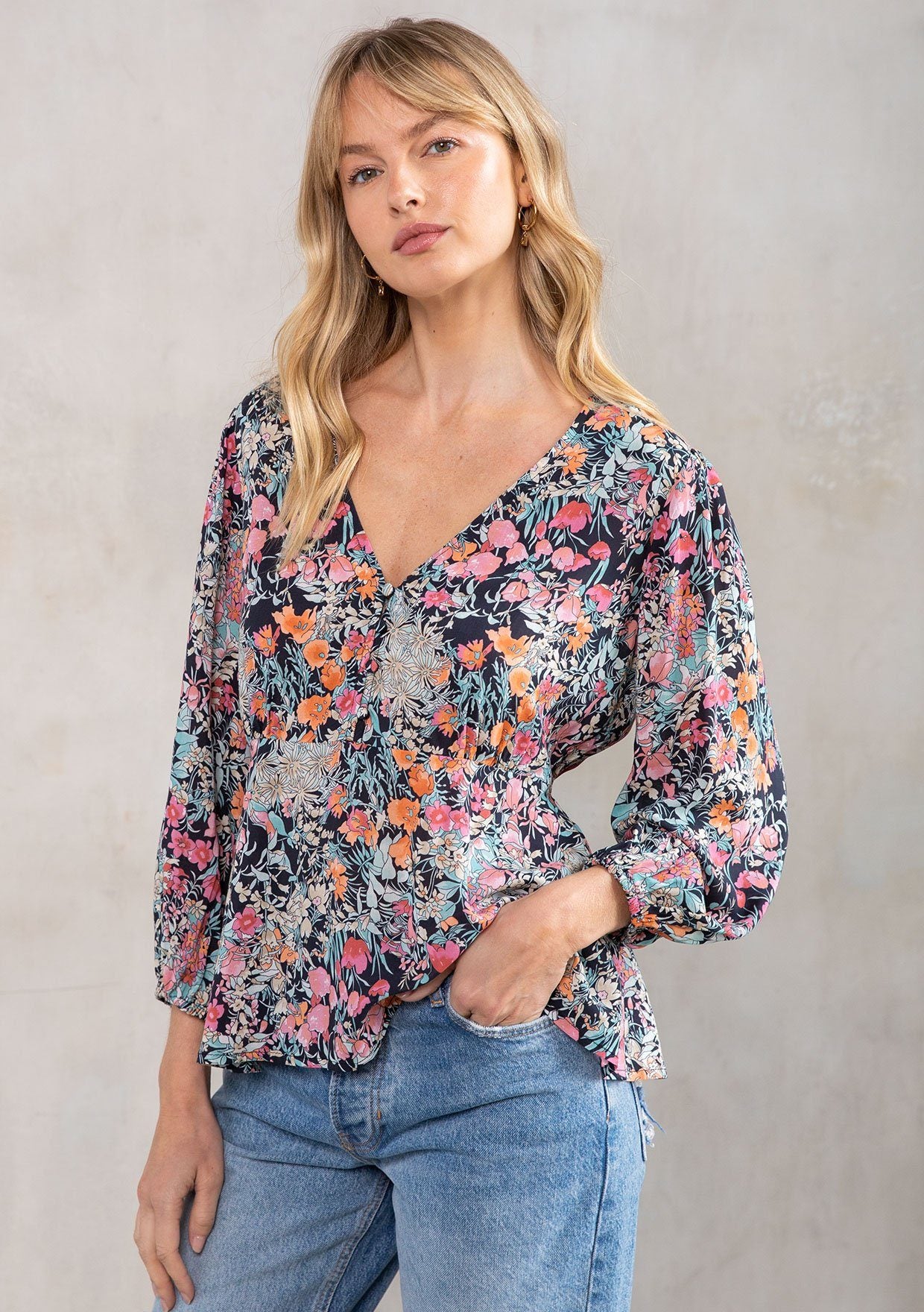 [Color: Black/Pink] A model wearing a versatile bohemian black and pink vintage floral print blouse. With a peplum waist, voluminous three quarter length sleeves, and a self covered button front.