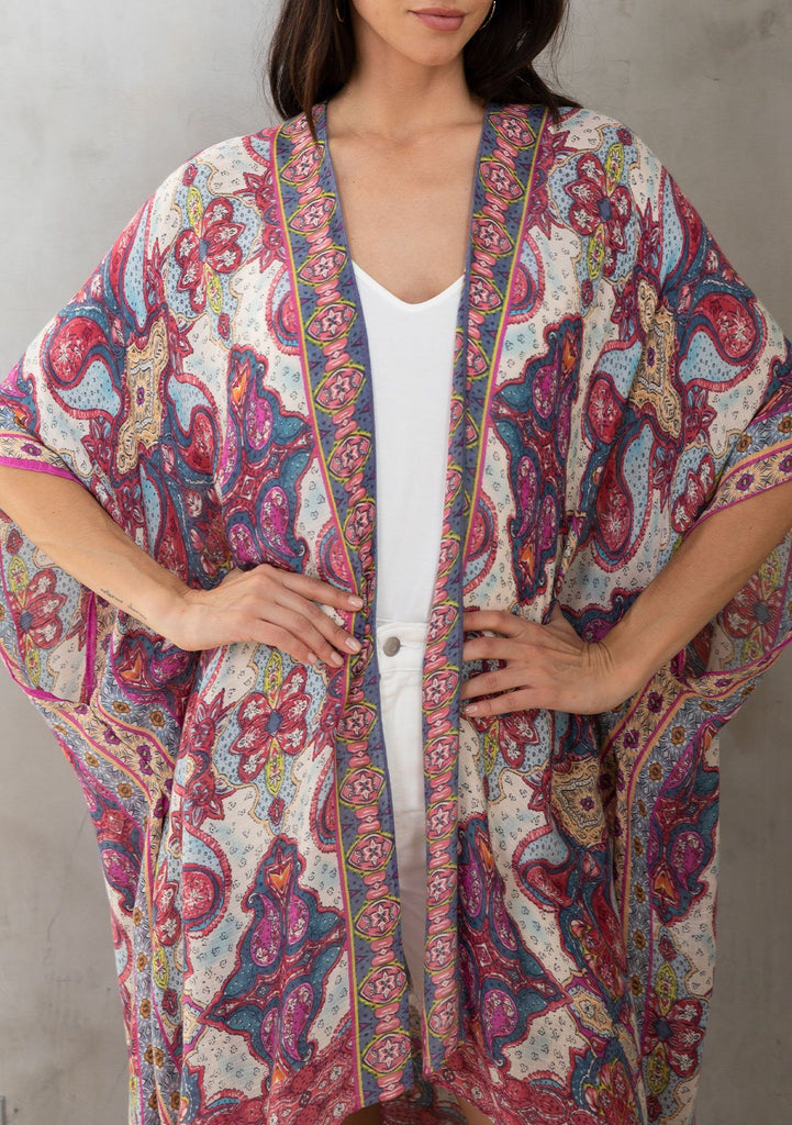 [Color: Blue/Fuchsia] A model wearing a dreamy blue and pink mixed print mid length kimono. A lightweight and soft bohemian style with half length sleeves, an open front, and side slits.