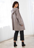 [Color: Mocha/Grey] A model wearing a cozy mocha brown oversize mid length cardigan. With side pockets, an open front, a shawl collar, and a hoodie. 