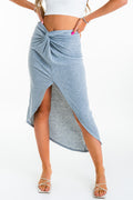 Falda midi canalé de fit ajustado, cintura alta con nudo frontal y abertura. Detalle de bajo curveado.