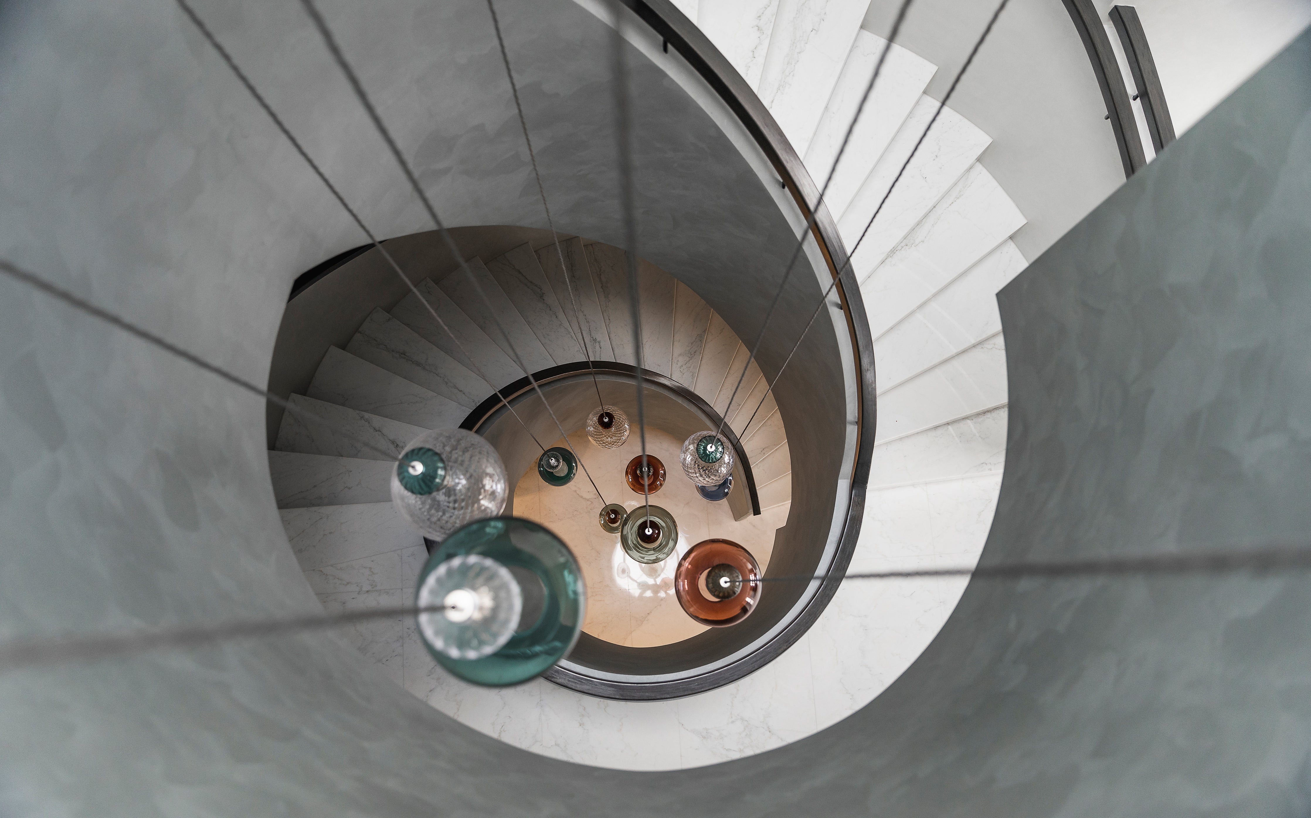 Glass pendant lighting by Rothschild &amp; Bickers hanging down spiral staircase