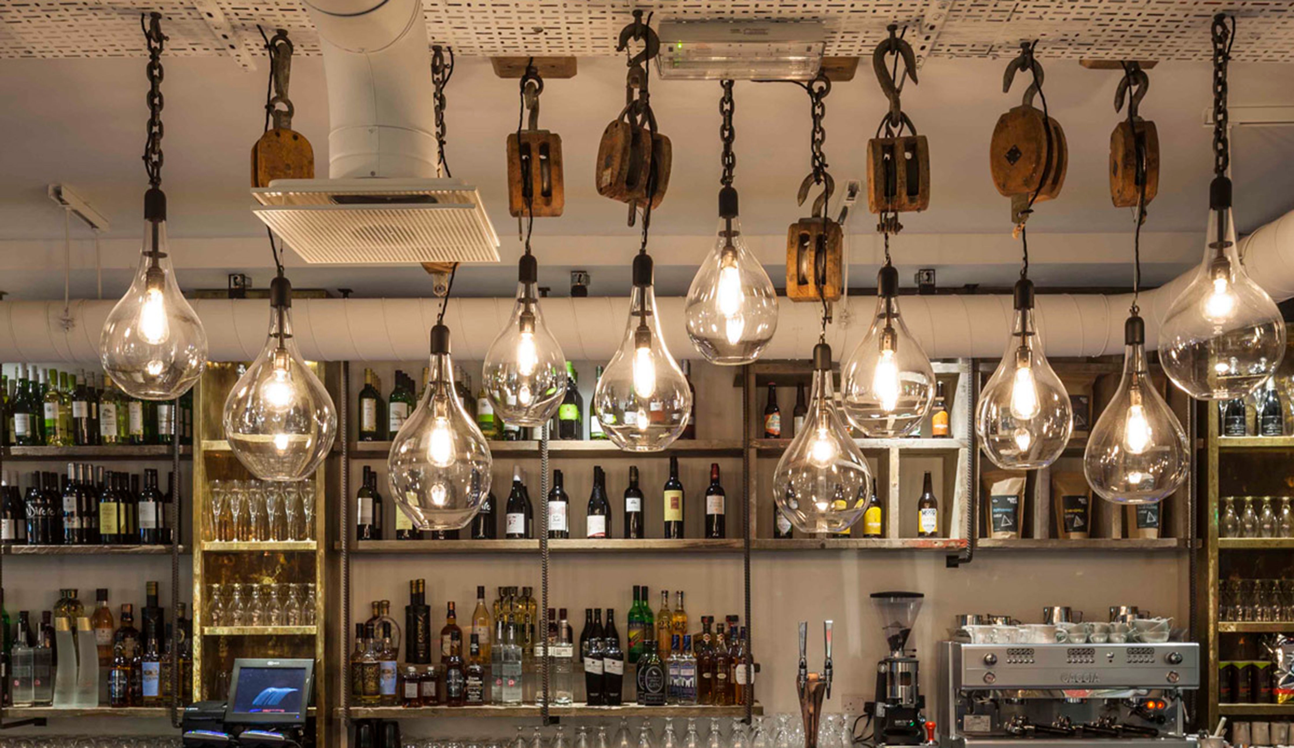 Bespoke glass pendants by Rothschild &amp; Bickers hanging over bar at Whyte &amp; Brown London