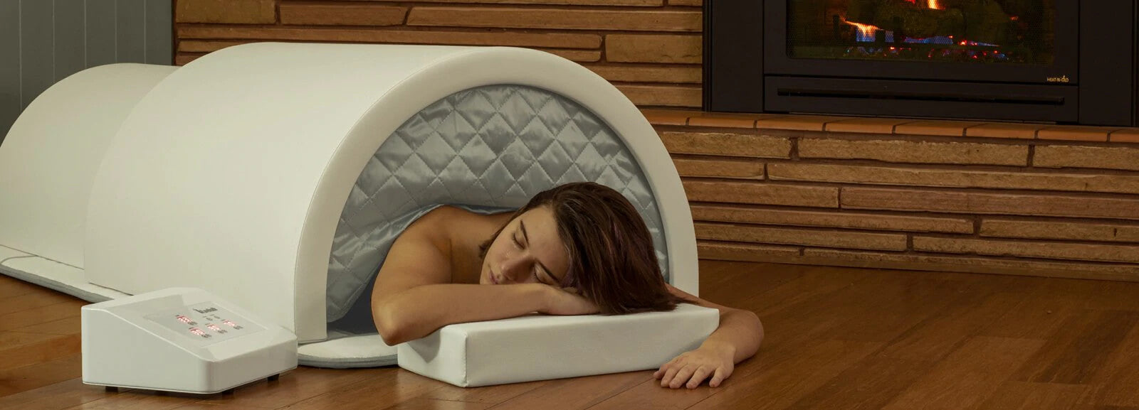 Woman enjoying a 1Love sauna on a hardwood floor in front of a fireplace