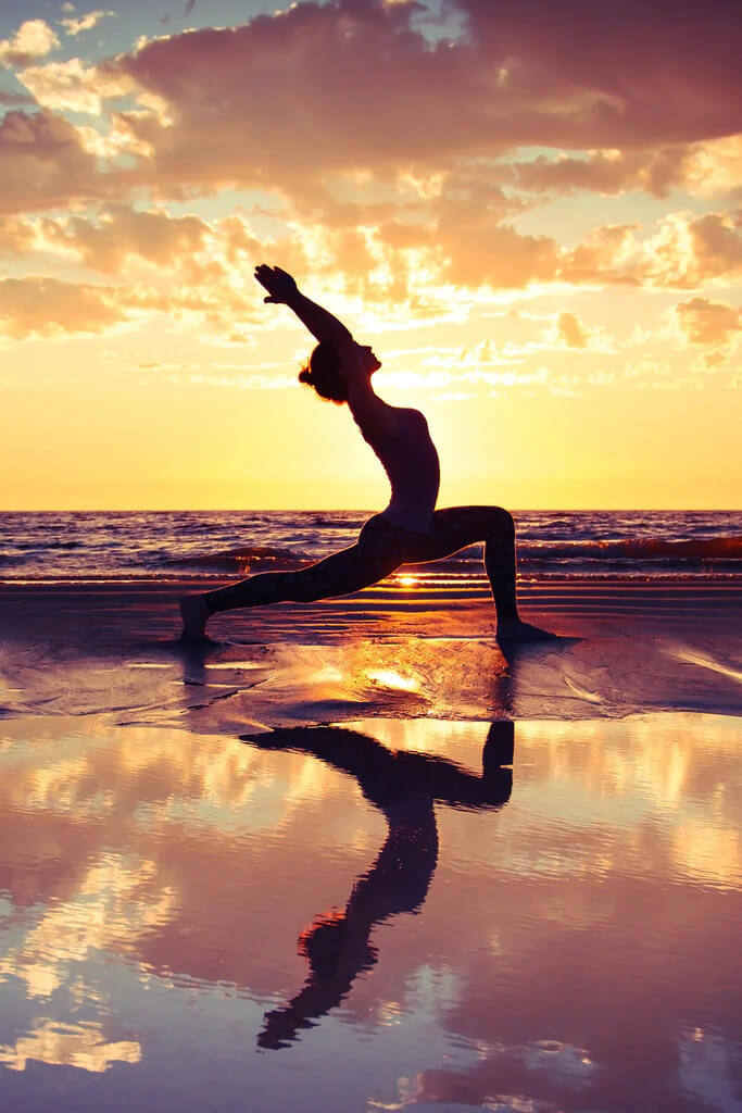 a woman practicing yoga on a beach for improved health