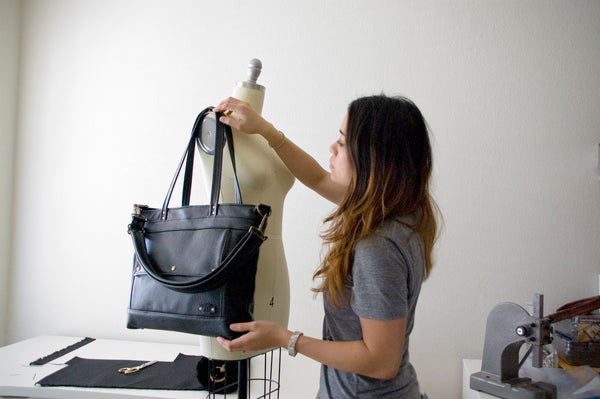 Photo of Jenny Nemlekar setting up a mannequin  with the Archive Tote Bag in Onyx black for a photoshoot