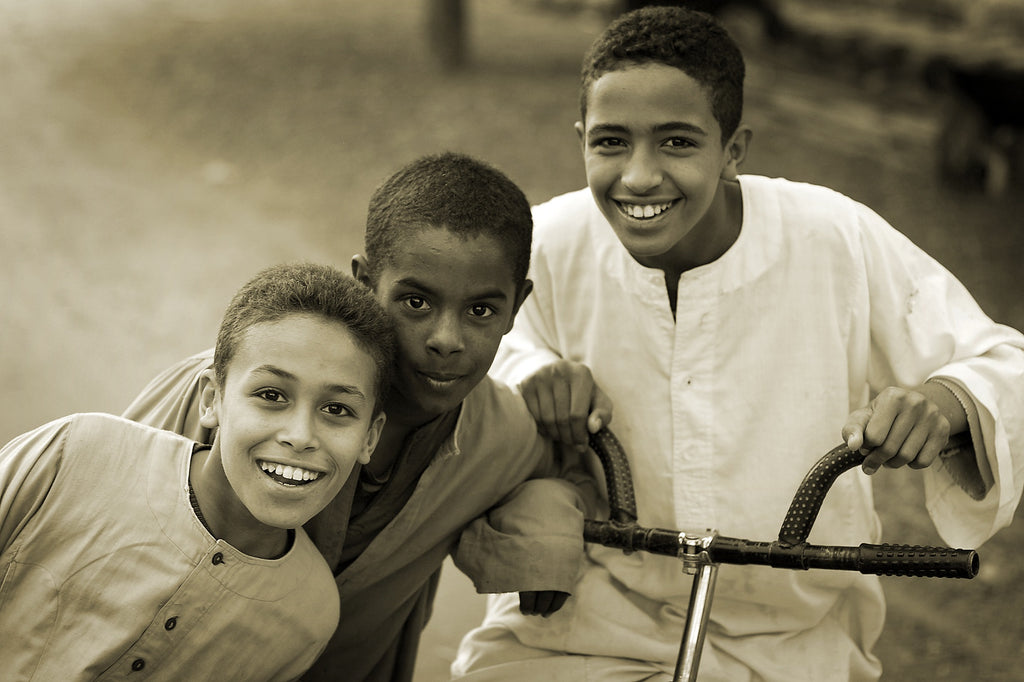 3 Arab boys smiling and looking at the camera.