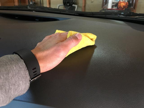 Wiping the dashboard of a toyota camry clean with a yellow microfiber towel