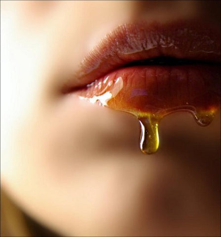 A close up image of honey dripping from a beautiful woman's lips