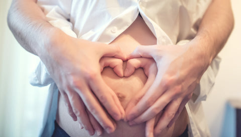 pregnant belly with hands in the shape of a heart