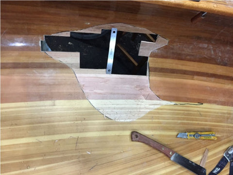 Hole in canoe hull with ruler for scale
