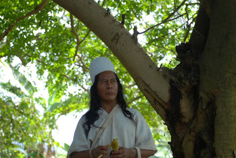 Mamo Camilo holding a gourd and stick for sacred coca medicine