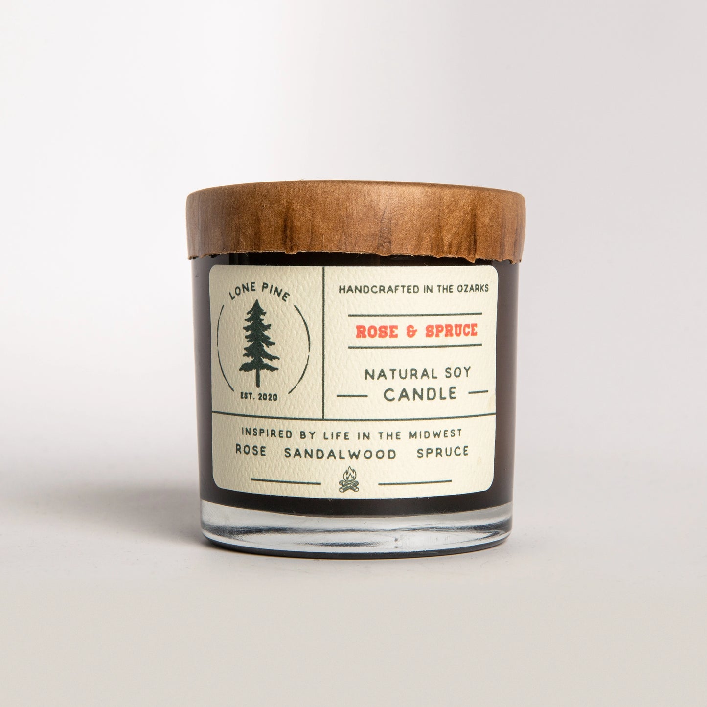 Rose and spruce-scented candle with a paper cap, made by Lone Pine.