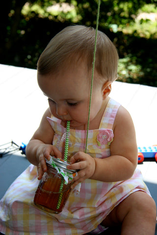 little girl drinking sweet tea from mason jar with green chevron paper straw and floral jar cover