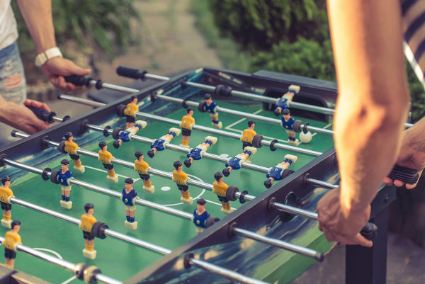 People playing and competing on a popular indoor foosball table.