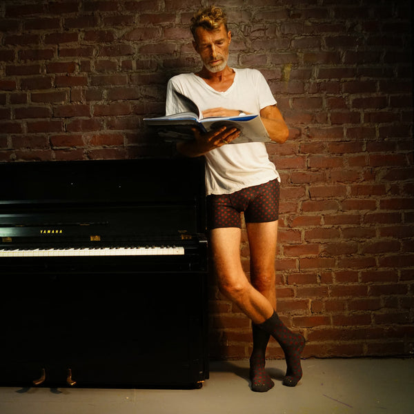 Rudy in RLTD mens underwear and socks standing next to a piano. 