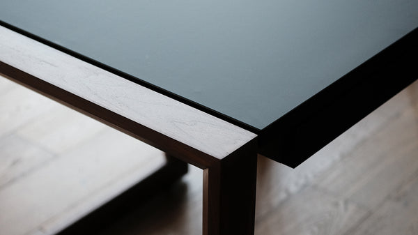 驼背风格的桌子胡桃木腿和超级光滑和哑光黑色桌面.