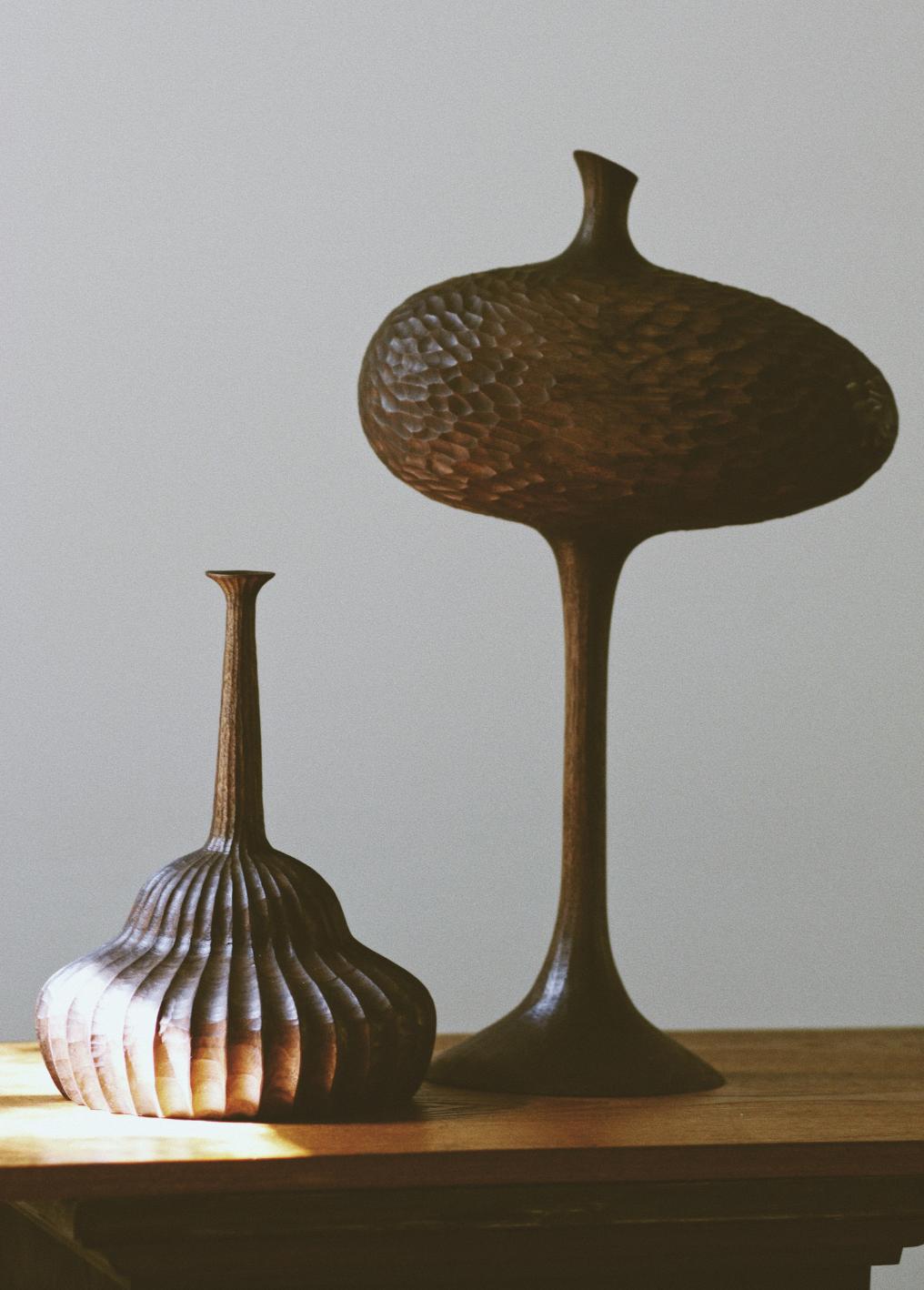 A collection of sculptural wooden objects on a wooden tabletop against a white background 