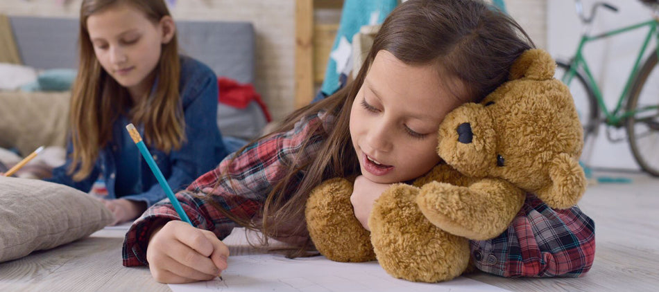 Child Holding Teddy Bear and Drawing Picture