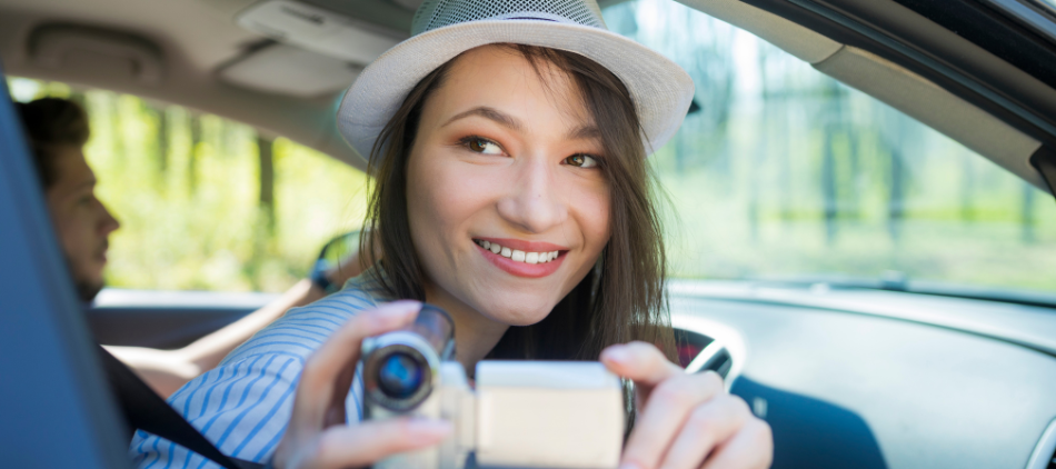 Woman leaning out of car videotaping