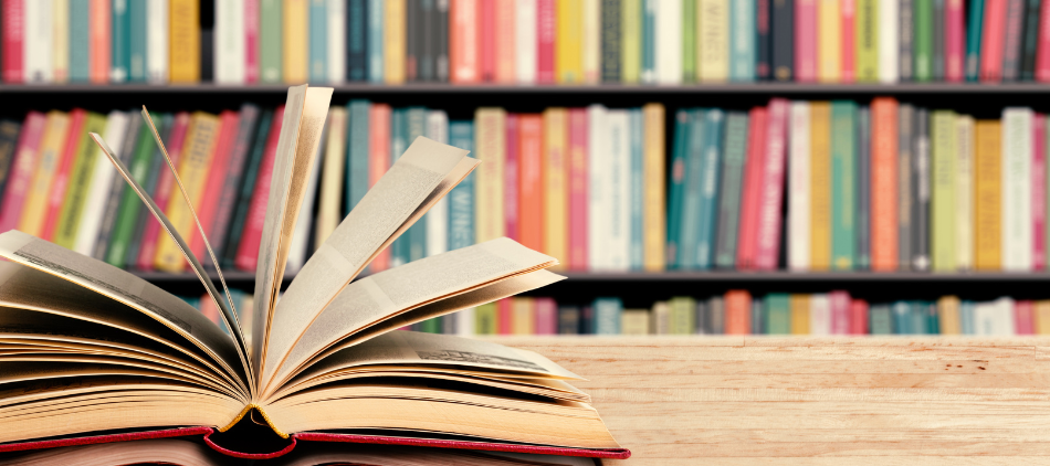 Open book on table with bookshelves in the background