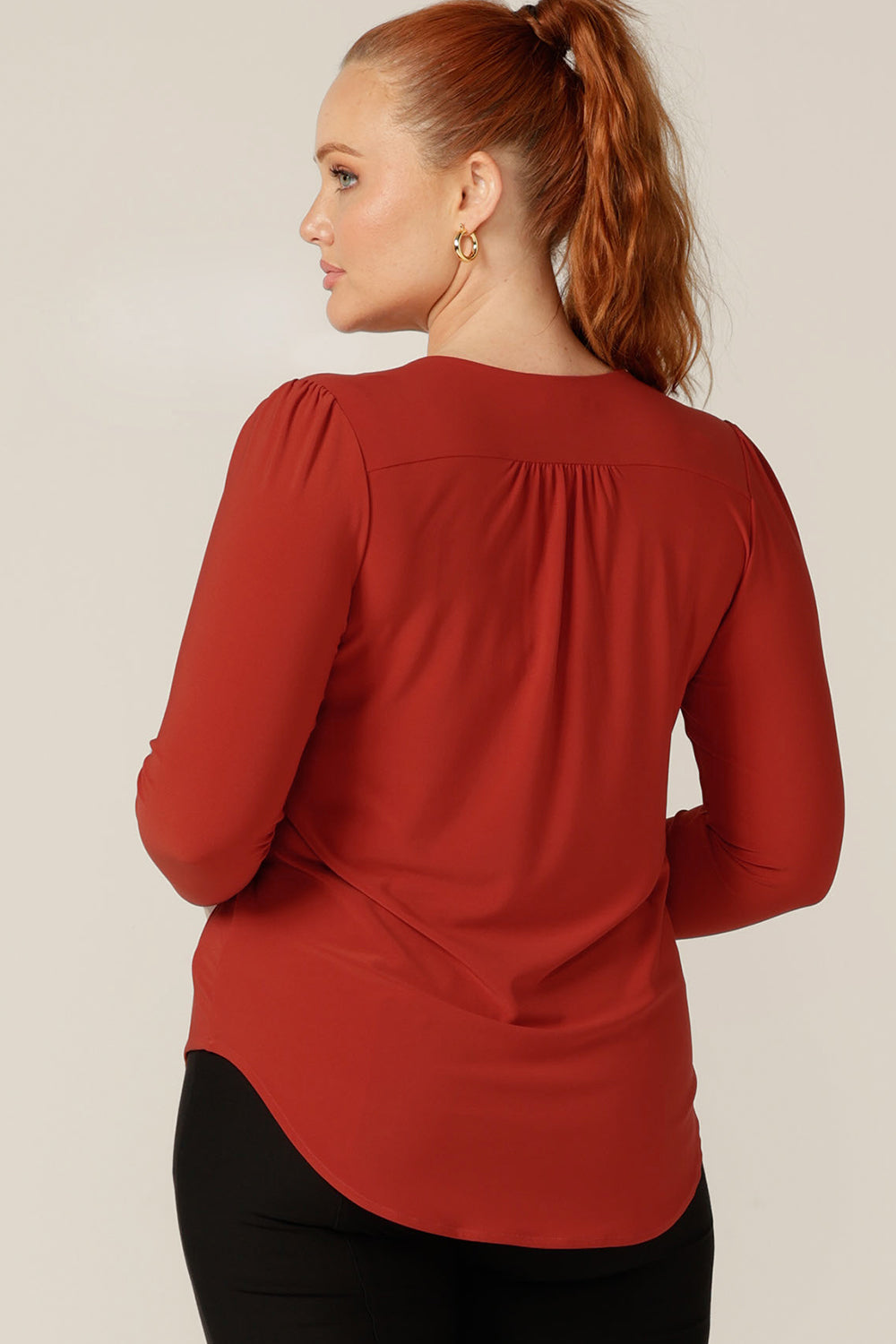Back view of Auatralian and New Zealand women's clothing label, L&F's newest workwear top.  A good top for petite to fuller figure women, this V-neck jersey top has long sleeves. In orange dry-touch jersey, this comfortable top is good for revitalising corporate suits and trousers..