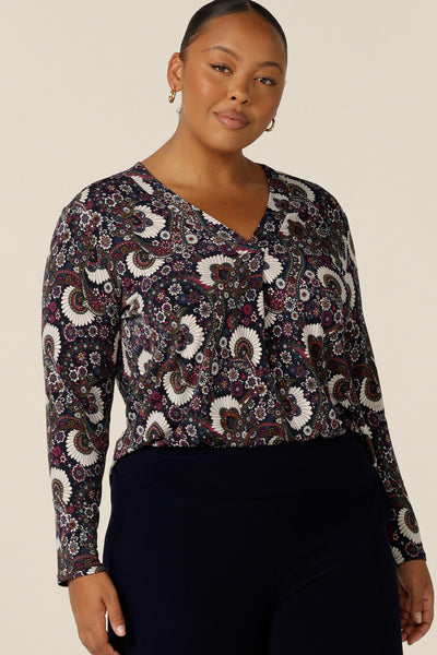 A size 18 woman wears a long-sleeve, V-neck top in paisley print jersey. Made in Australia by Australian and New Zealand women's clothing label, L&F this is a great top for work and is available to shop in sizes 8 to 24.