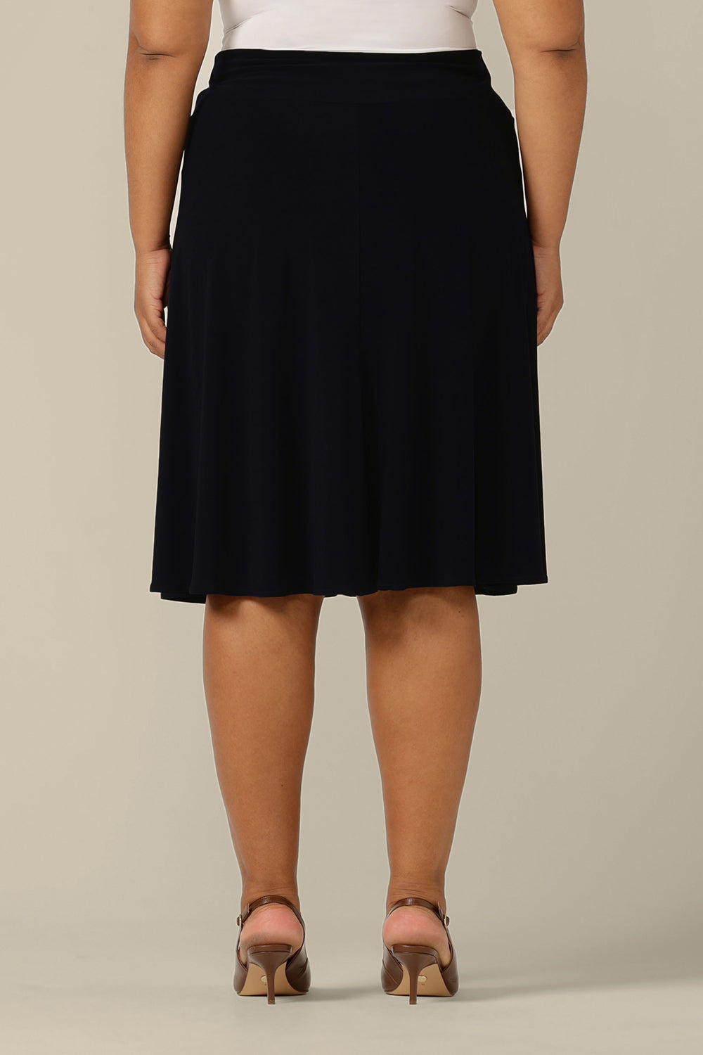 Back view of a fuller figure, size 18 woman wears a knee length pull-on skirt in navy jersey by Australian and New Zealand women's clothing brand, L&F. A classic skirt for comfortable work wear or smart casual wear.