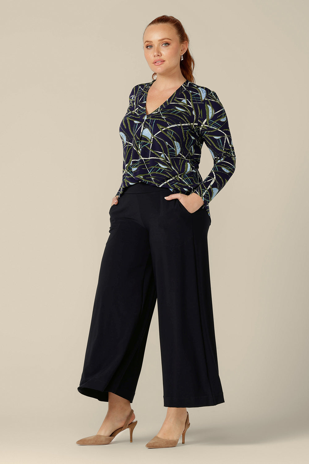The Dakota Top in Willow is by Australian and New Zealand women's clothing label, L&F. This top has a V-neck with front tuck below that looks great under workwear jackets. Long sleeves make the Dakota Top a good winter top. With a navy-base print, this top is worn here with wide leg , navy trousers. Shop in inclusive sizes, 8-24.
