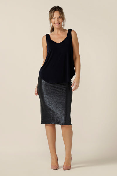 A 40 plus woman wears a navy cami top with wide shoulder straps and a sparkly tube skirt. Made in Australia by Australian and New Zealand women's clothing company, this slinky jersey top wears well with evening and occasionwear skirts, pants and suit jackets.