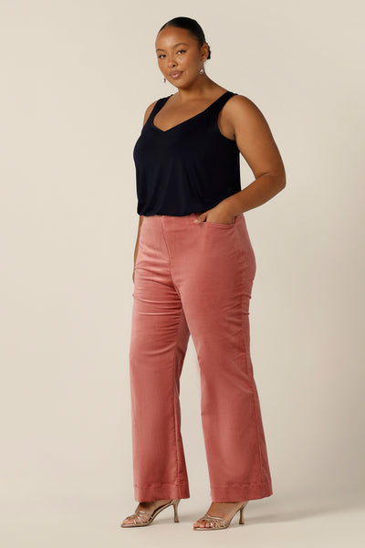A size 18, plus size woman wears a navy cami top with wide shoulder straps together with flared, pink velvet trousers. Made in Australia by Australian and New Zealand women's fashion label, L&F, this slinky jersey top wears well with evening and occasionwear skirts, pants and suit jackets.