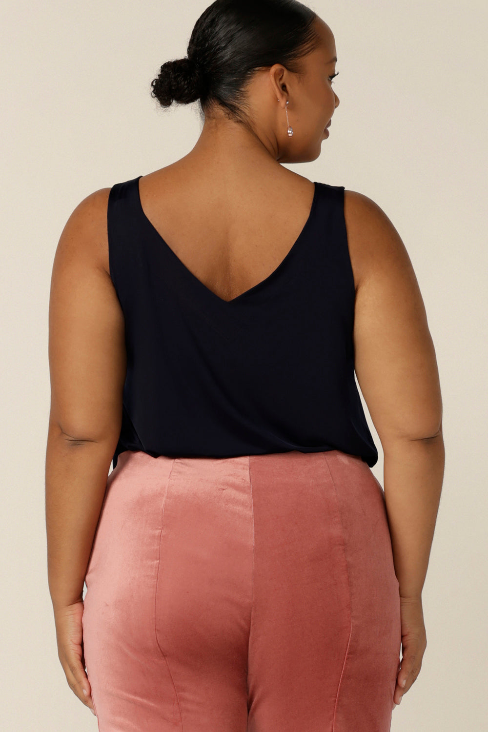 Back view of a size 18, fuller figure woman wearing a V-back, navy cami top with wide shoulder straps. Made in Australia by Australian and New Zealand women's clothing company, this slinky jersey top wears well with evening and occasionwear skirts, pants and suit jackets.