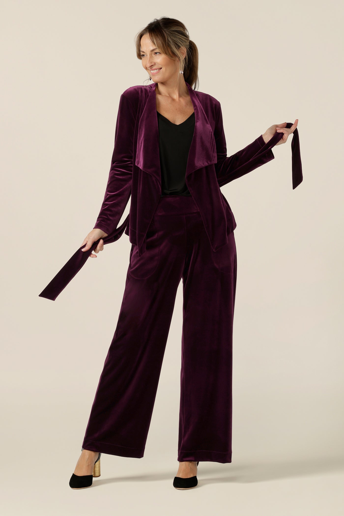 Occasionwear dressing at its finest, this soft tailoring jacket in red wine velour adds effortless glamour to black cocktail wear. Shown here over a black cami top and slim leg black trousers, this open front, soft collared evening jacket is made in Australia in sizes 8 to 24.