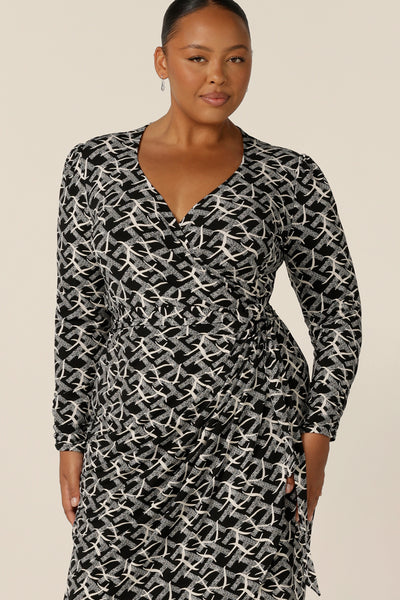 A long sleeve, black and white print, wrap dress with tulip skirt by Australian and New Zealand women's clothing brand, L&F. Worn by a fuller figure woman, this jersey wrap dress is available to shop in inclusive sizes, 8 to 24.
