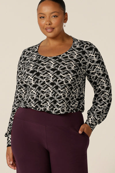 A size 18, plus size woman wears a long sleeve top with bishop sleeve cuffs and a scoop neck in black and white print jersey. Made in Australia by Australian and New Zealand women's clothing brand, L&F this women's work top is available to shop in sizes 8 to 24.